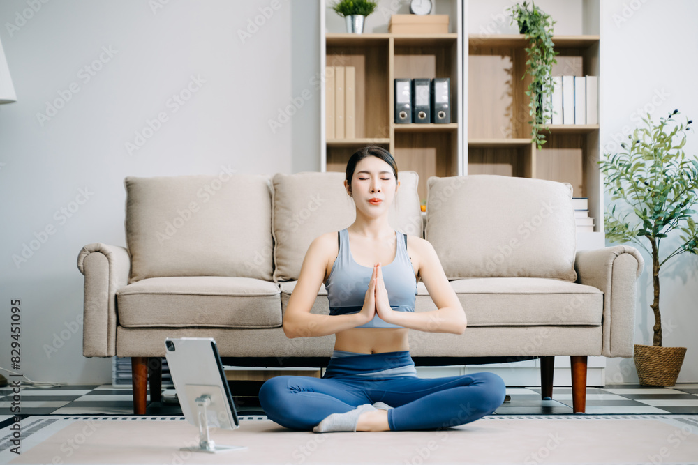 Asian Woman Doing Yoga and Watching Online Tutorials on Laptop, Training in Living Room at home Asian Woman Doing Yoga and Watching Online Tutorials on Laptop, Training in Living Room at home
