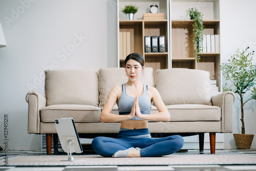 Asian Woman Doing Yoga and Watching Online Tutorials on Laptop, Training in Living Room at home