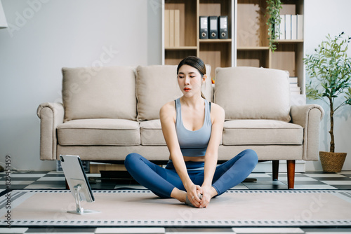 Asian Woman Doing Yoga and Watching Online Tutorials on Laptop, Training in Living Room at home