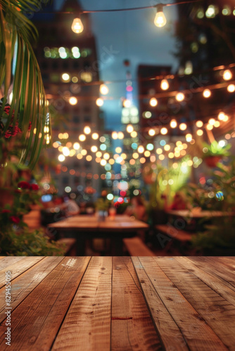 A wooden bar top in the foreground with a blurred background of an urban rooftop bar. The background includes stylish seating, plants, string lights, a panoramic city view.