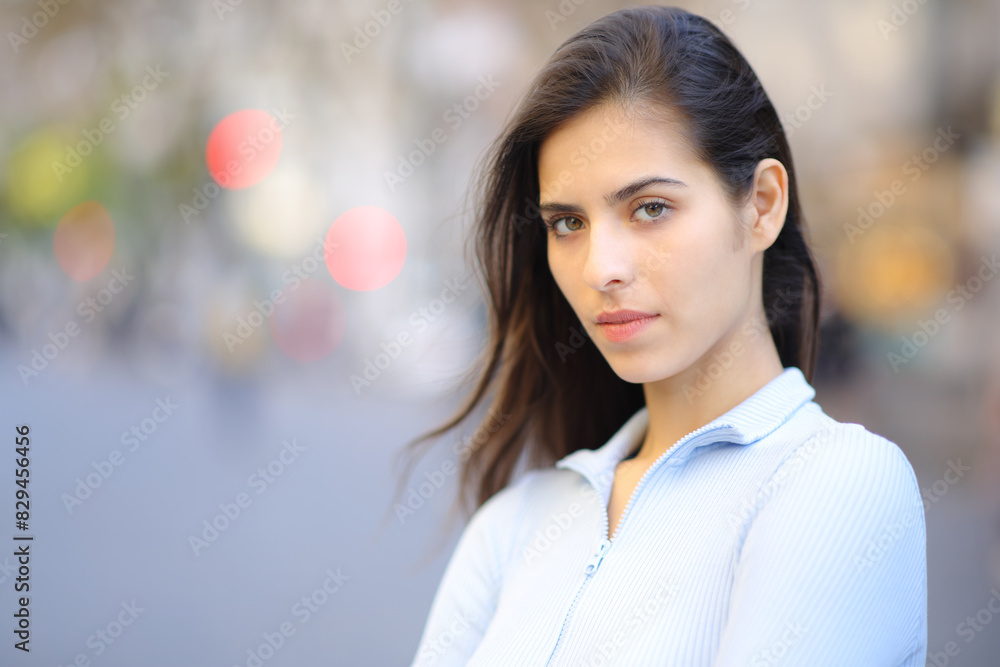 Serious woman looks at camera standing in the street Serious woman looks at camera standing in the street