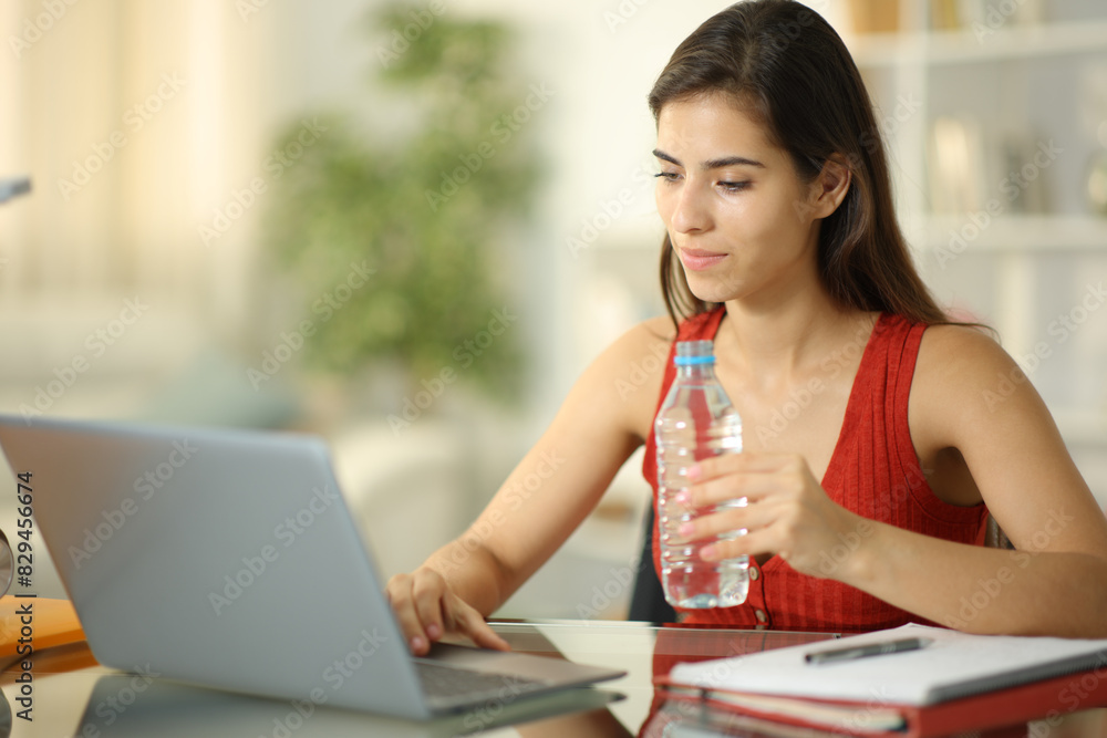 Student drinking water from bottle at home Student drinking water from bottle at home