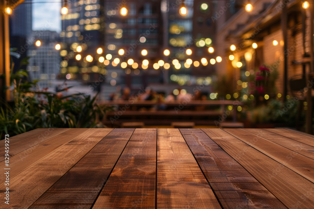 A wooden bar top in the foreground with a blurred background of an urban rooftop bar. The background includes stylish seating, plants, string lights, a panoramic city view.