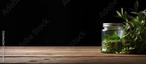 A copy space image featuring green tea leaves and a tea canister resting on a wooden table photo