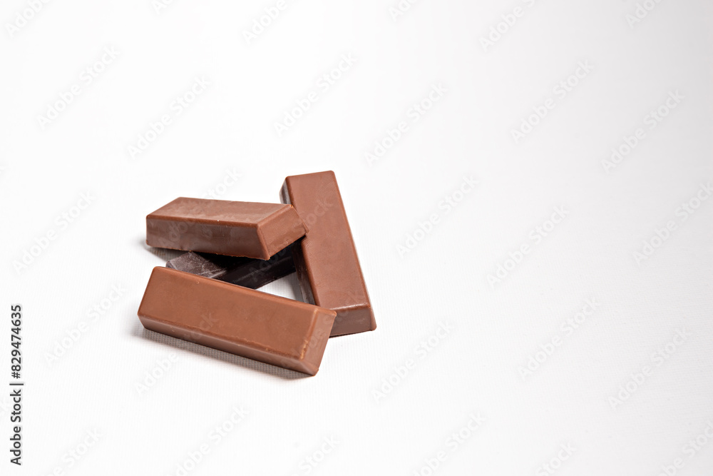 Fototapeta premium chocolate pieces on white,Milk chocolate pieces isolated on white background, chocolate pieces, cocoa dessert slices