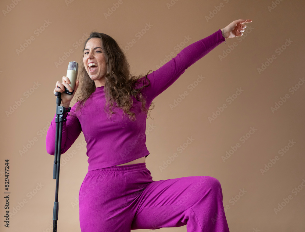Passionate singer holding microphone against beige background Passionate singer holding microphone against beige background