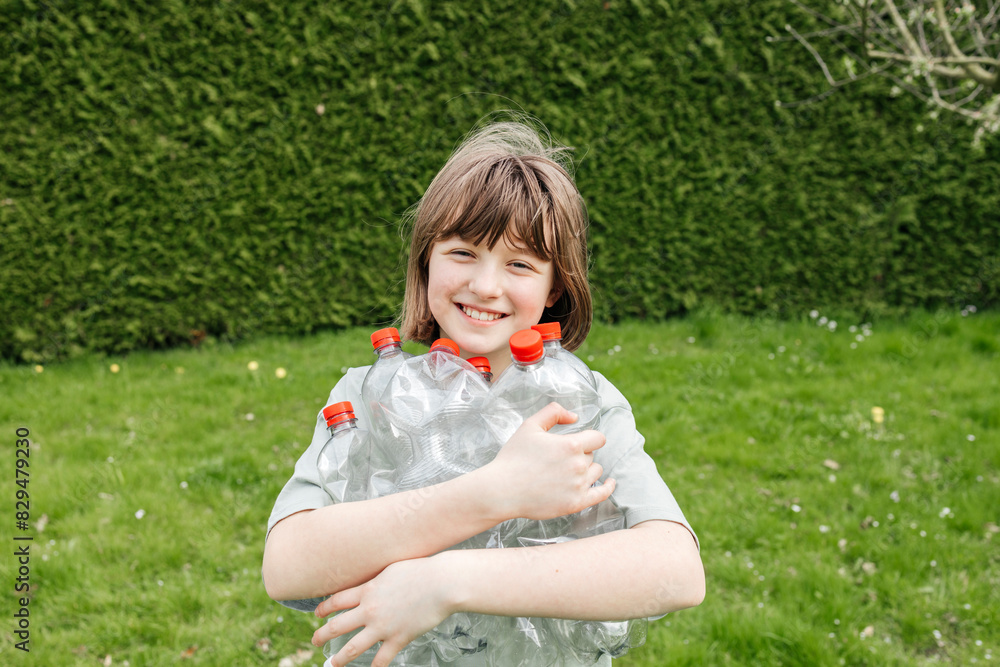 Smiling girl holding empty plastic bottles collected for recycling Smiling girl holding empty plastic bottles collected for recycling