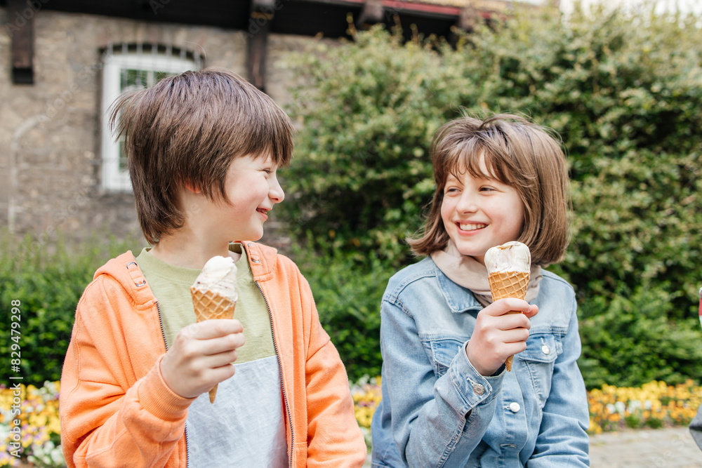 Happy brother and sister enjoying ice cream near plants