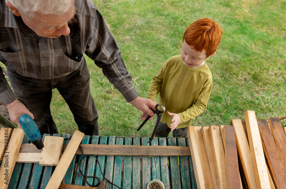 Grandfather giving tool to grandson at back yard Grandfather giving tool to grandson at back yard