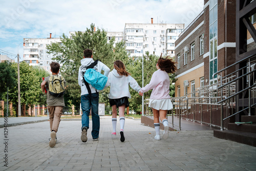 Teenage boys and girls running side by side at schoolyard photo