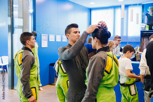 Instructor tying hair of woman in changing room at indoor skydiving center photo