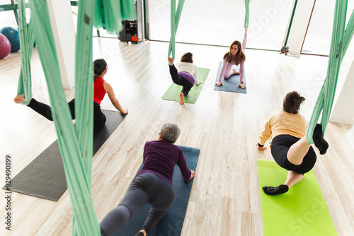 Yoga instructor with women practicing stretching exercise on aerial silk Fabric and mat in class photo