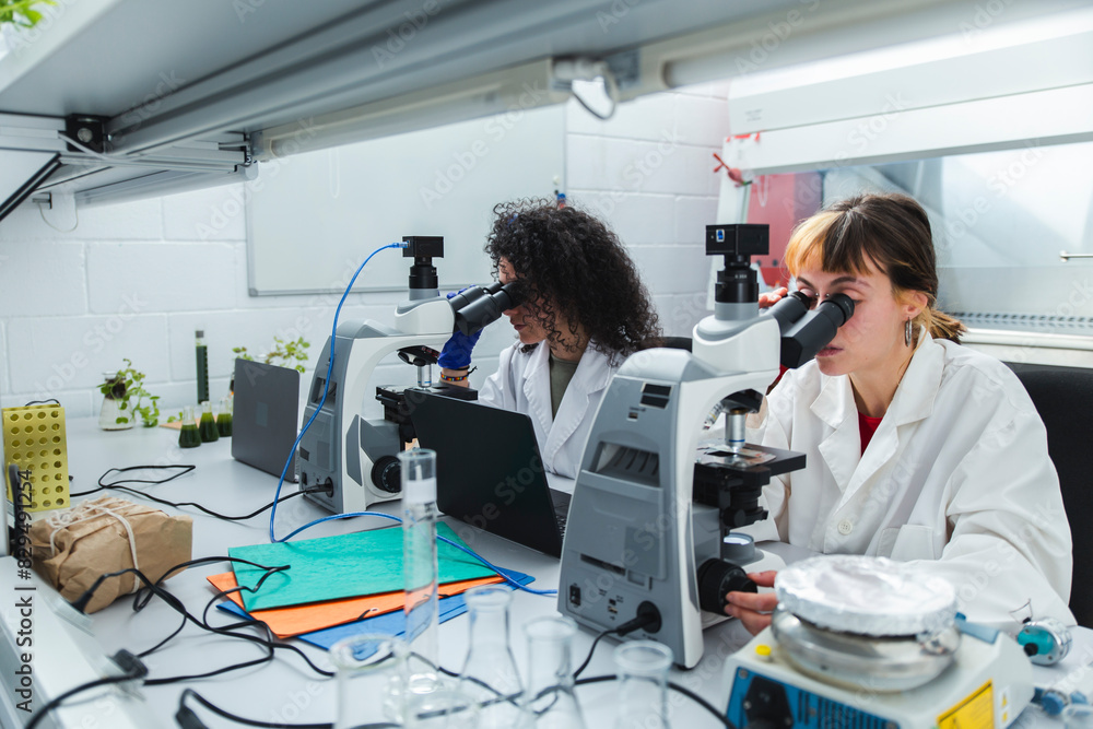 Young scientists looking through microscopes in laboratory Young scientists looking through microscopes in laboratory