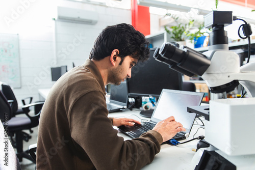 Confident scientist using laptop in lab office photo