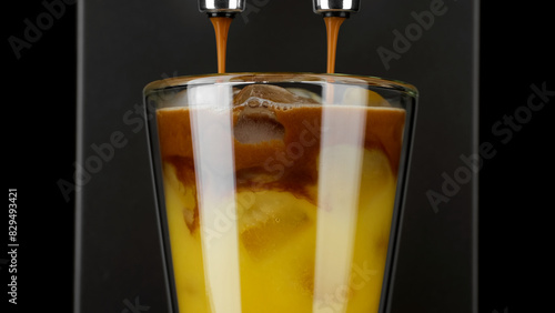 Pouring black coffee in glass with orange juice and ice cubes. Espresso orange juice drink