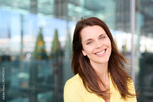 Smiling woman with brown hair wearing yellow shirt at airport photo