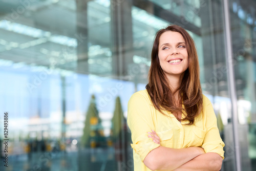 Woman wearing yellow shirt with arms crossed at airport