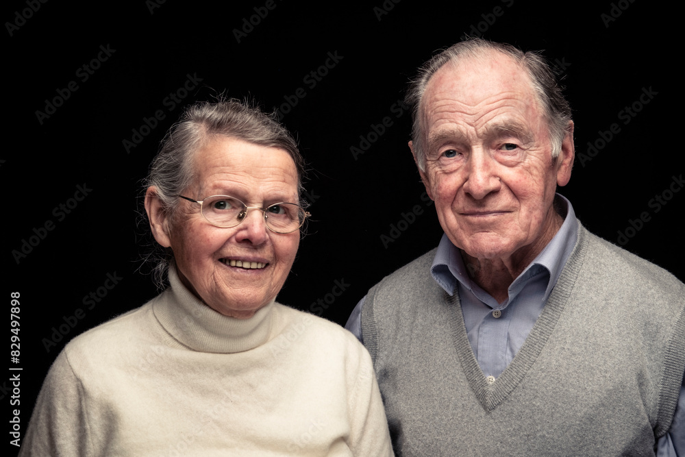 Senior couple smiling against black background Senior couple smiling against black background