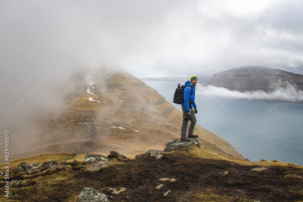 Happy man standing on rock at mountains of Klakkur, Faroe islands Happy man standing on rock at mountains of Klakkur, Faroe islands