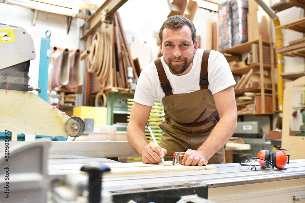 portrait of a carpenter in work clothes and hearing protection in the workshop of a carpenter's shop portrait of a carpenter in work clothes and hearing protection in the workshop of a carpenter's shop