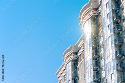 modern real estate building apartment high exterior design from perspective point of view with panoramic blue sky vivid colors empty space and sun light glare effect from glass