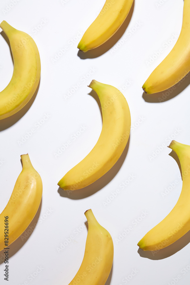 Unique template of banana theme for natural fruit origin products promotion, plenty yellow bananas neatly arranged on the white flat. The photo was taken from high angle shot with space for design