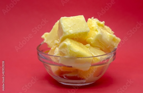 Milk Butter in a Small Glass Bowl Isolated on Red Background with Copy Space
