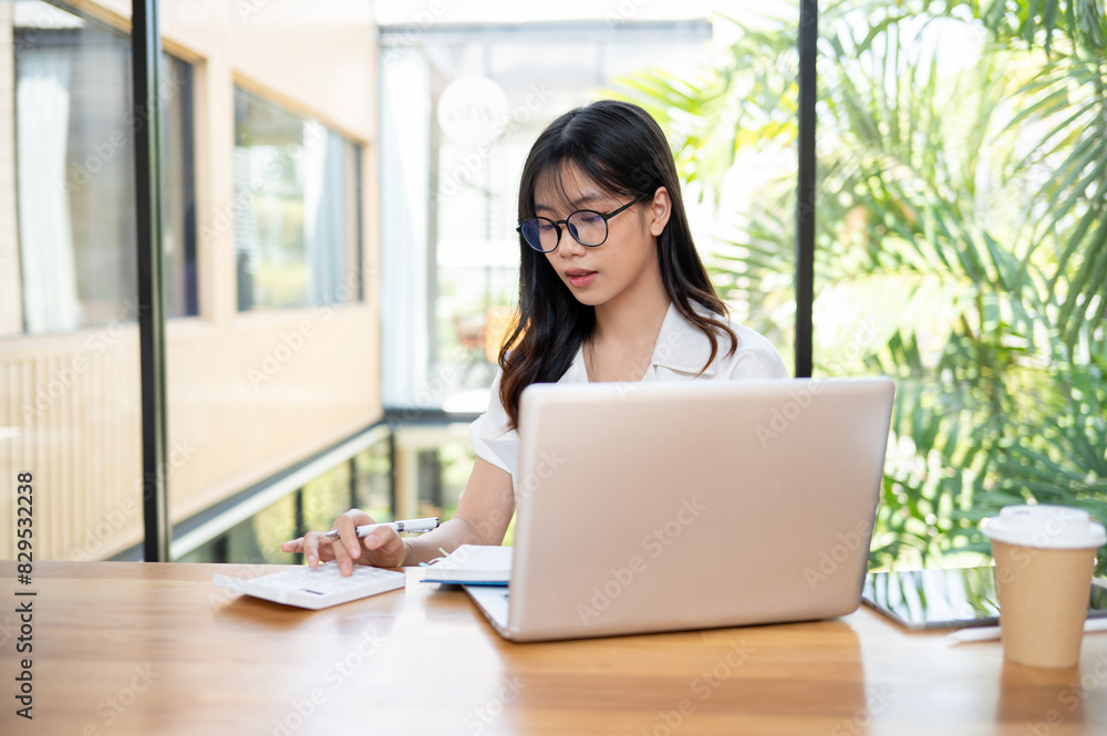 A beautiful Asian businesswoman is using a calculator, focusing on calculating business expenses. A beautiful Asian businesswoman is using a calculator, focusing on calculating business expenses.