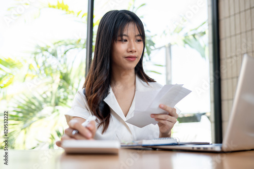 Free Download A female accountant is checking bills and receipts, working on business financial data on her laptop - GFXLoad