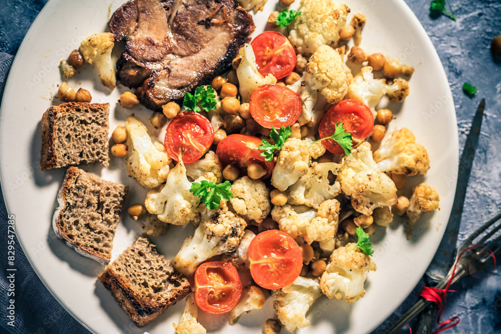 Fototapeta premium Delicious dinner cauliflower baked chickpeas tomatoes meat art toasts