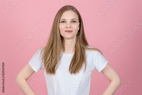 Portrait of attractive caucasian young blonde woman in casual white t-shirt isolated on pink background. Smiling, and looking at the camera with pleasure. Lifestyle, natural beauty