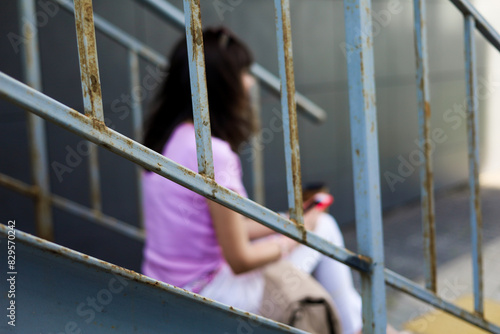 Image of beautiful woman sitting on street stairs on summer day and holding mobile phone