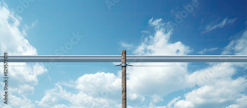 A cable stretches across poles under a lightly cloudy blue sky in a copy space image photo