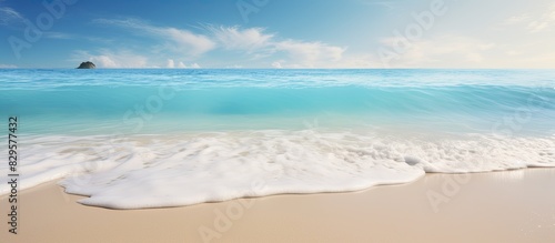 Gentle blue ocean wave washing up on a pristine sandy beach with copy space image