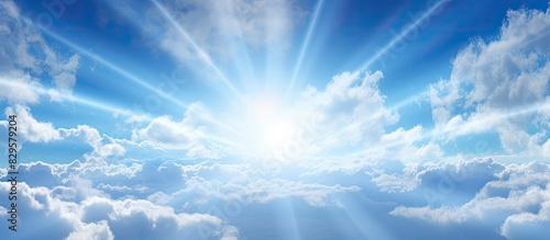Fototapeta Naklejka Na Ścianę i Meble -  Bright sun rays beaming through fluffy clouds in a clear blue sky creating a picturesque scene with copy space image