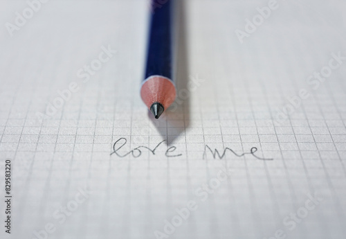 Words LOVE ME on paper and pencil
