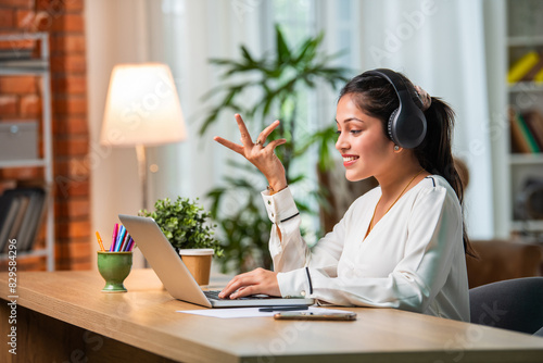 Indian asian young beautiful female business woman working on laptop on table or desk photo