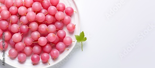 Top view of pink gooseberries on a white plate creating a vibrant copy space image for summer food with a berry harvest theme