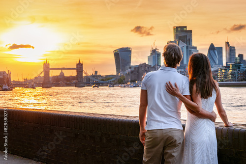 A romantic tourist couple enjoys the beautiful sunset view of the skyline of London, England