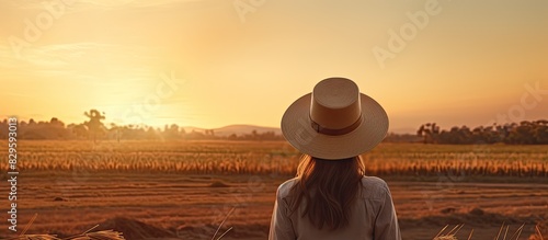 A woman in agribusiness attire sporting a hat and jeans is seen at the conclusion of her workday in a rural setting with a beautiful sunset background in the copy space image photo