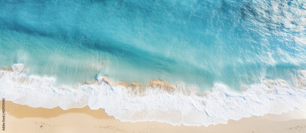 A view from above of a sandy beach with light blue water waves and sunlight a summer vacation background with a relaxation theme and room for text or images. Copy space image A view from above of a sandy beach with light blue water waves and sunlight a summer vacation background with a relaxation theme and room for text or images. Copy space image