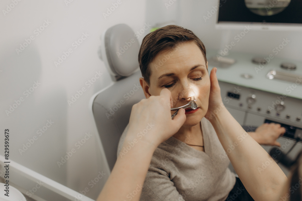 Rhinoscopy of woman nose. Consultation with ENT doctor. Otolaryngologist examines girl nose before procedure of endoscopy of nose Rhinoscopy of woman nose. Consultation with ENT doctor. Otolaryngologist examines girl nose before procedure of endoscopy of nose