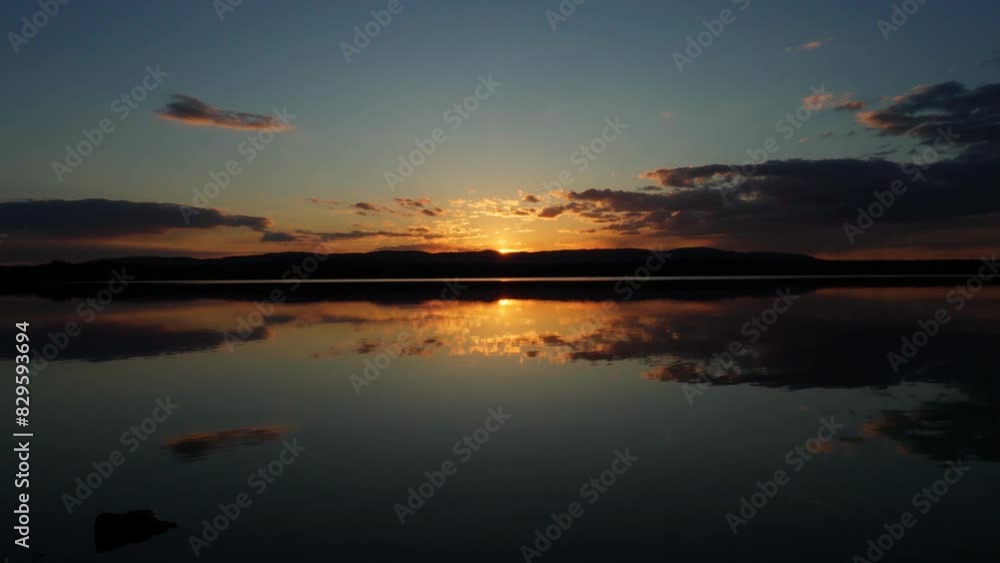 Sunset on the lake with a mirror image of the sky on the water. Landscape view of the lake, calm environment. Beauty is in nature.