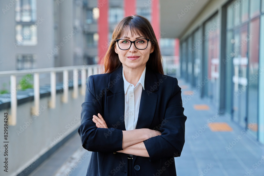 Mature confident business woman with crossed arms in black suit outdoors Mature confident business woman with crossed arms in black suit outdoors