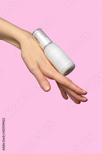 Woman hand showing cream product. Cosmetic product branding mockup. Daily skincare and body care routine. Female hand holding  cosmetic product mockup on a light pink background. Close up.