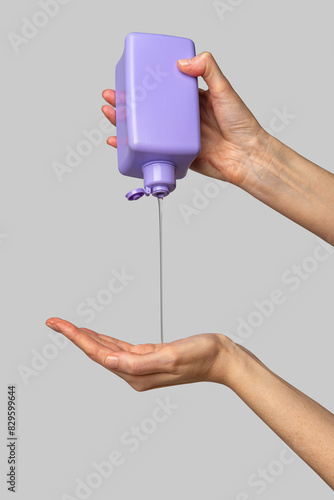 Woman hand showing a package of bath foam or shampoo. Cosmetic product branding mockup. Daily skincare and body care routine. Female hand holding  cosmetic product mockup on a light gray background.
