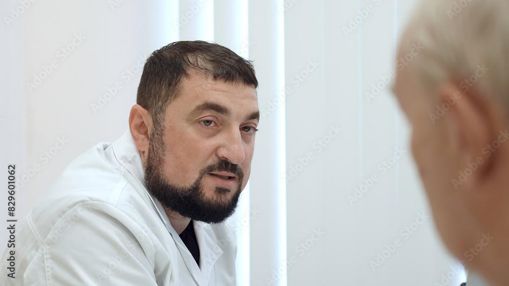 Fototapeta premium Elderly man at doctor's appointment. Clip. Grandpa is at doctor's appointment. Therapist prescribes treatment for elderly man