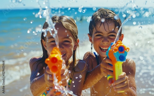 Two children having fun, shooting water with water guns in the sea, splashing around