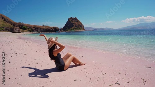Young female tourism enjoying the tropical pink sandy beach with clear turquoise water at Komodo islands in Indonesia