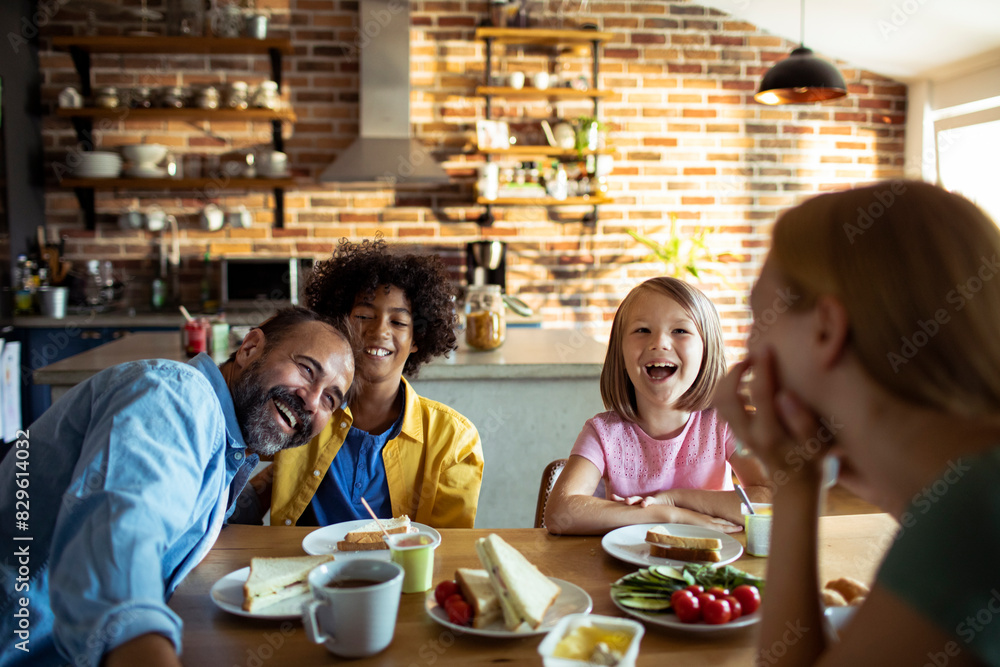 Multiracial family laughing together at breakfast table Multiracial family laughing together at breakfast table